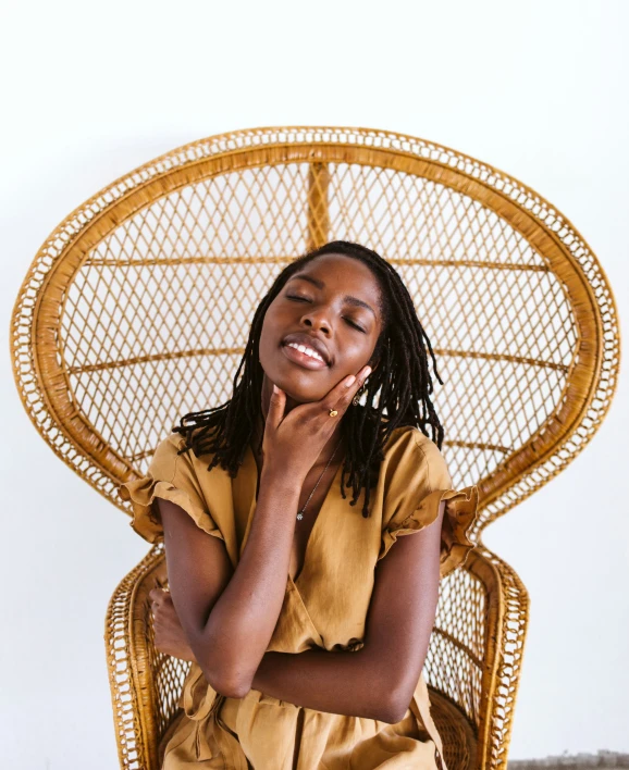 a woman sitting in a chair smiling, with her hands on her chin