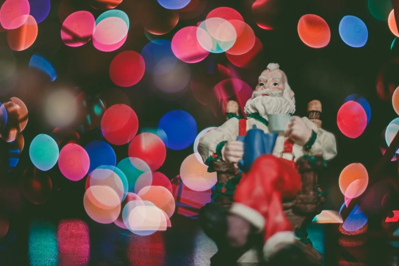 a figurine sitting on a bench in front of christmas lights