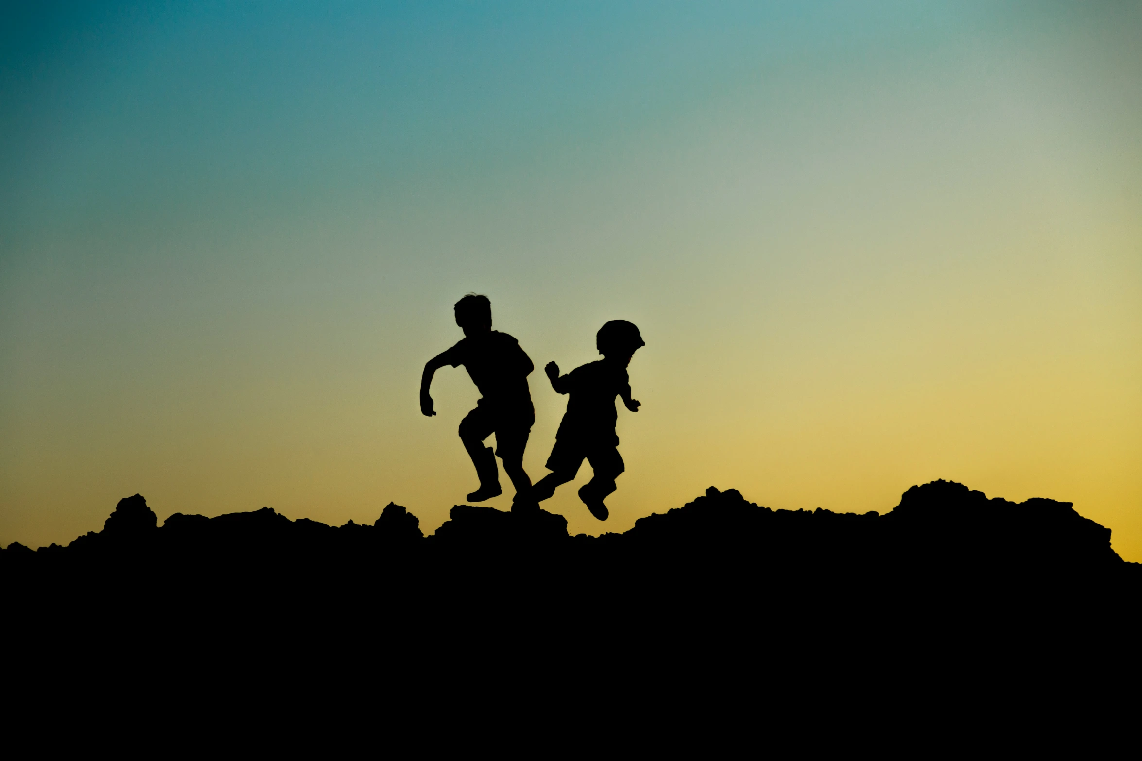 two people running in the field as the sun goes down