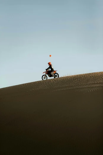 a person riding on the back of a motorcycle down a desert