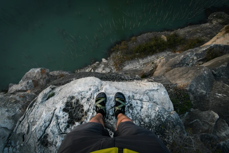 a man is sitting on top of a rock and has his feet up to the ground