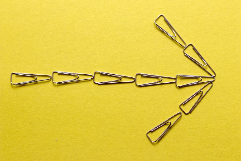 many pairs of metal clothes pins on a yellow surface