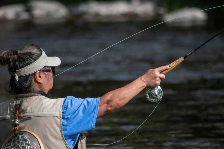 a man on a river with his arm out is holding a fishing rod