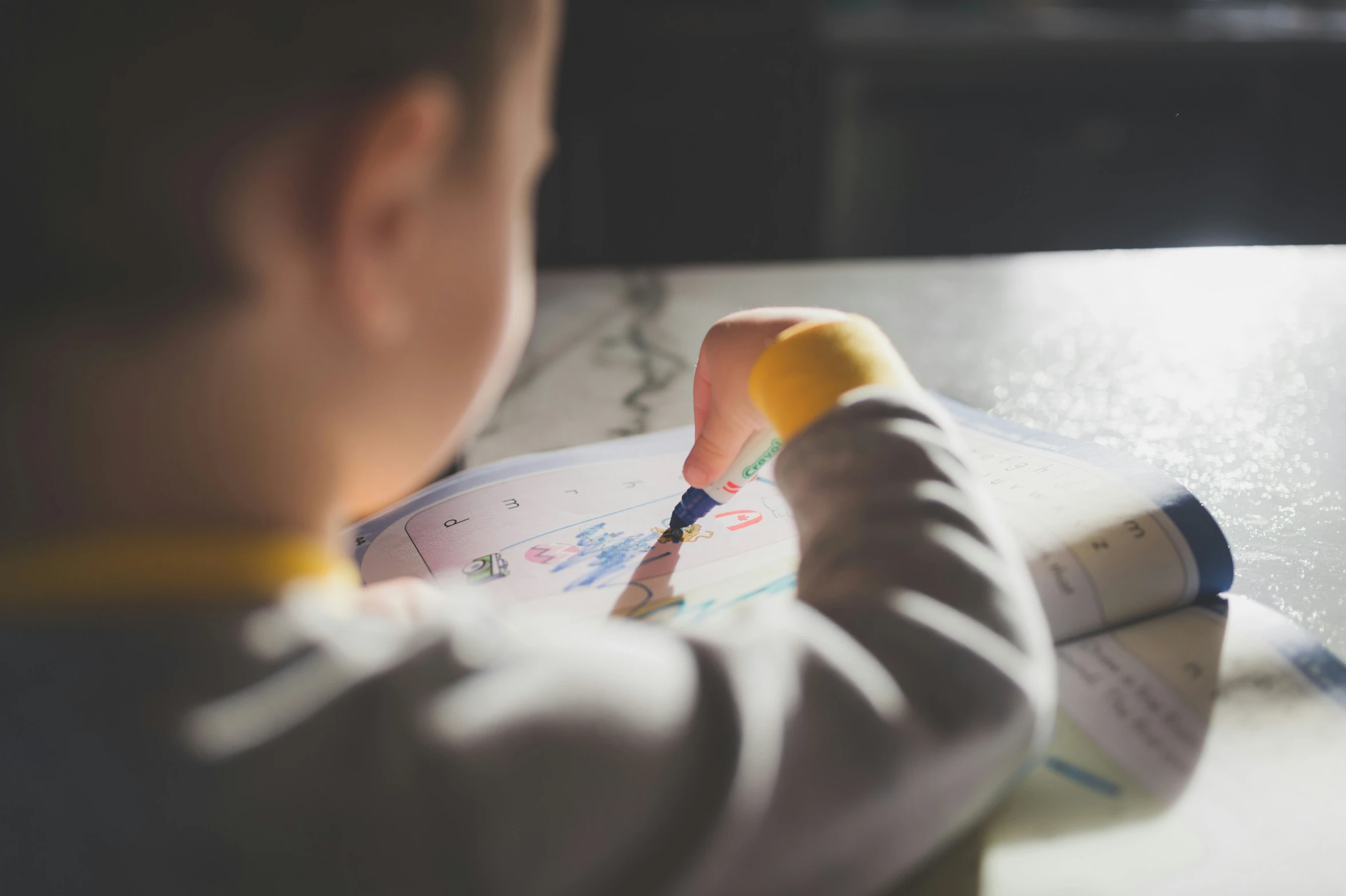 small child drawing on large white plate with color marker