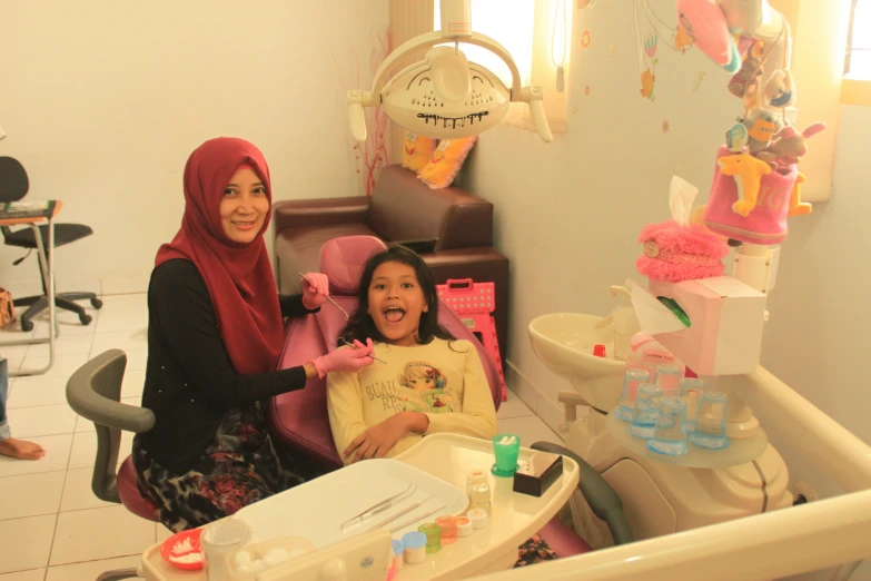 two girls sit in a chair next to some toys