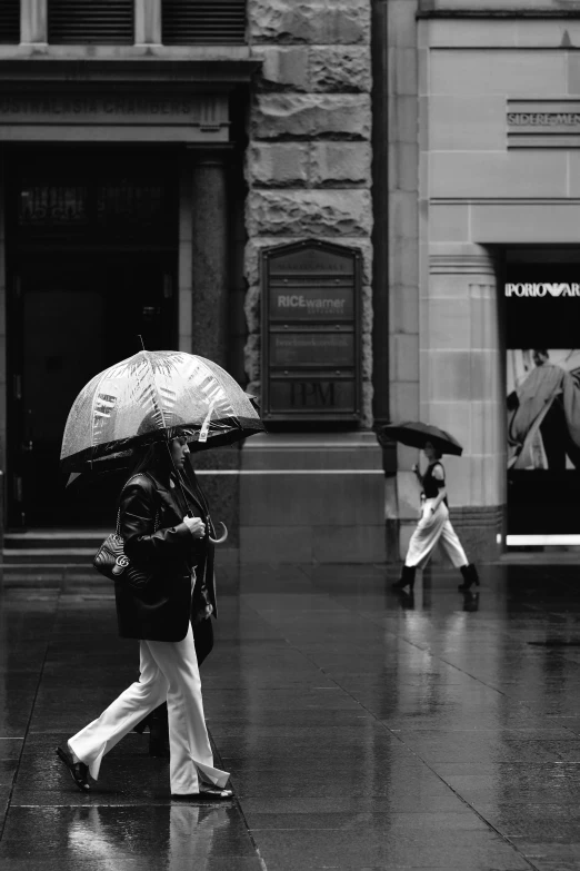 black and white image of people walking in the rain with umbrellas