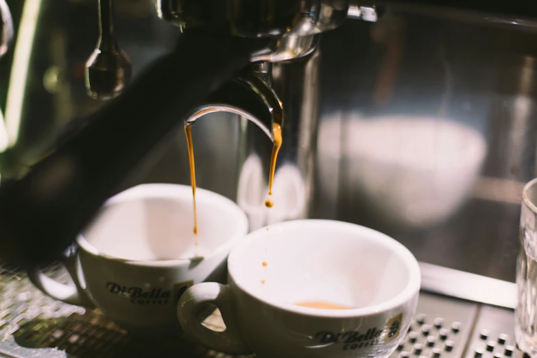 someone is making espresso at home and the coffee is in cups