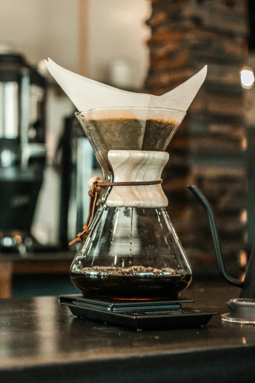 a chemekaffe with brown liquid in it is on a wooden table