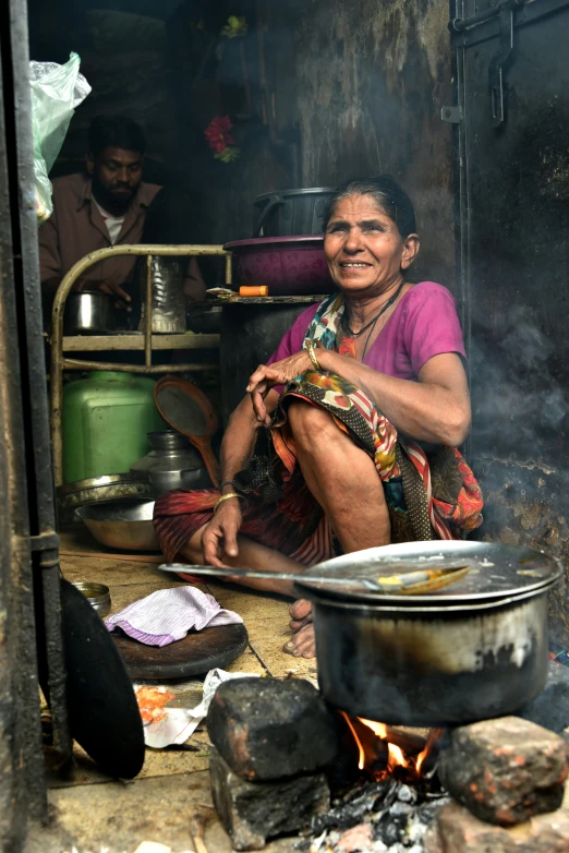 a woman sitting next to a big pot