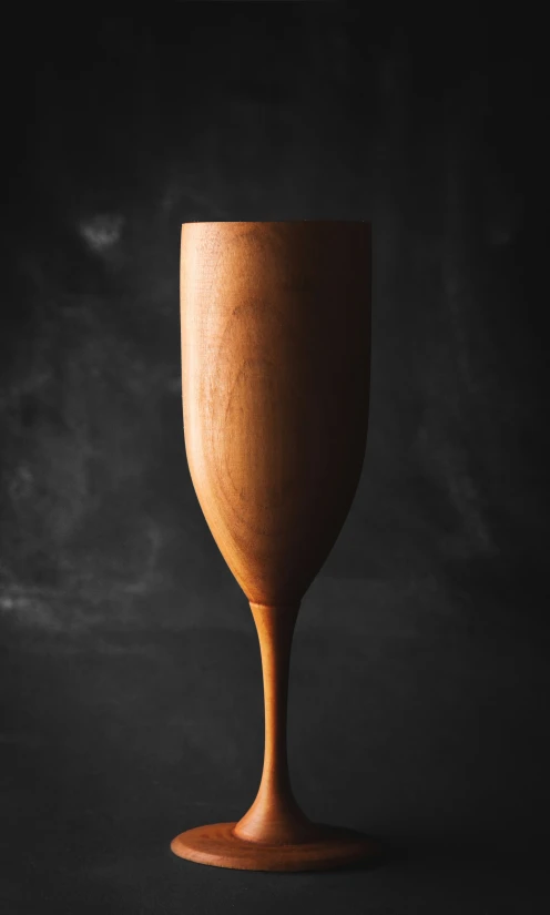 a wooden cup sitting on top of a dark surface