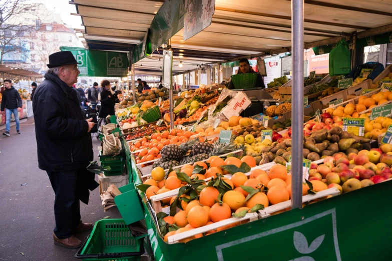 a man looking at oranges on display at an outdoor market