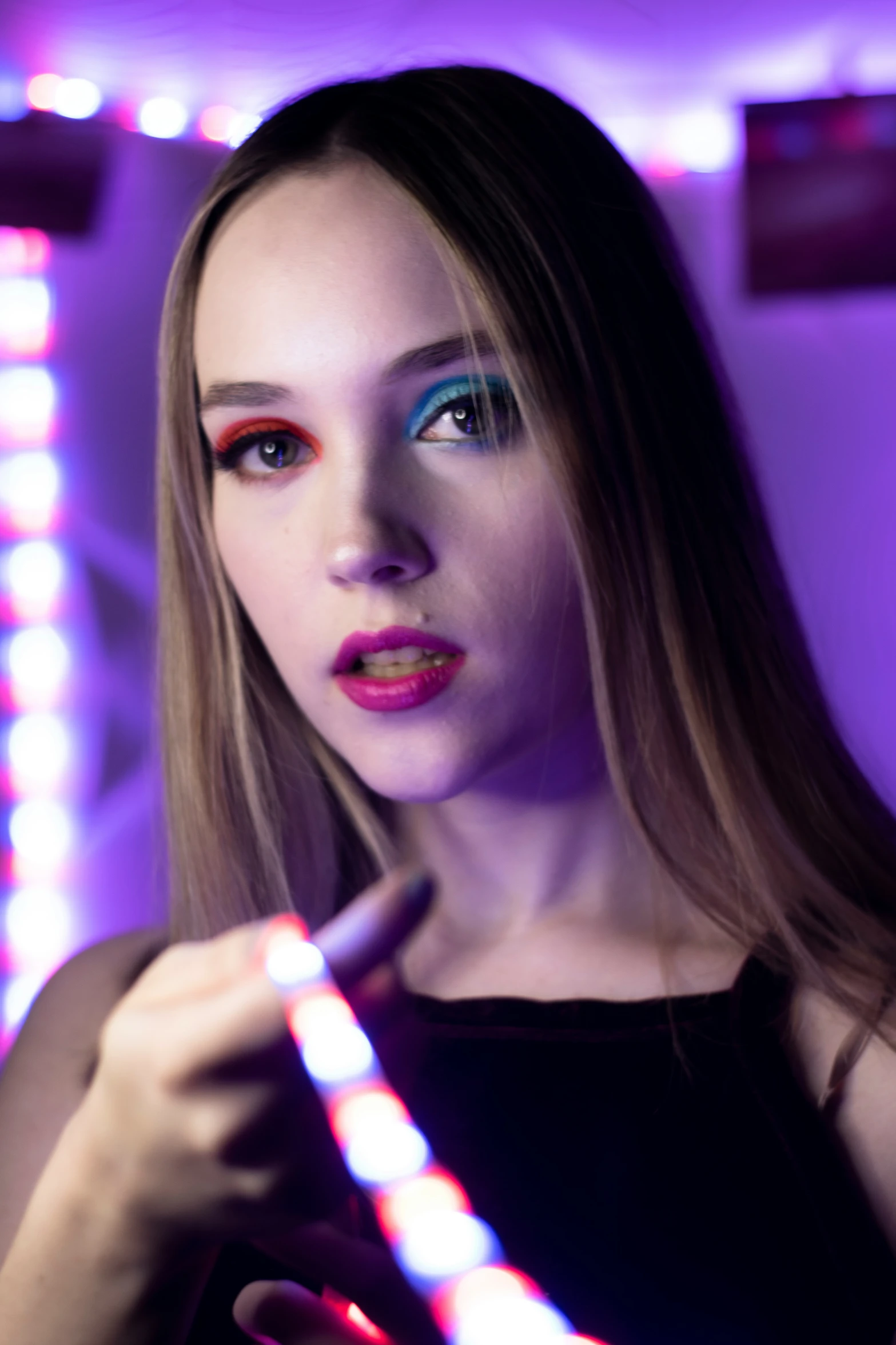 young woman with colorful makeup putting on colored make up