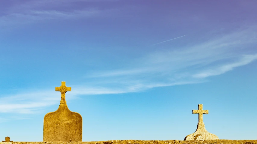 a cemetery with two crosses standing on a hill