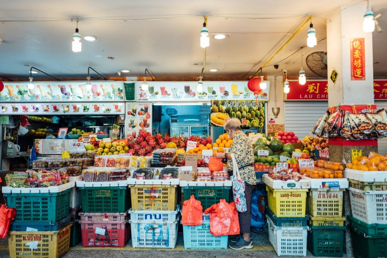 a woman is shopping in a market that sells many types of fruit