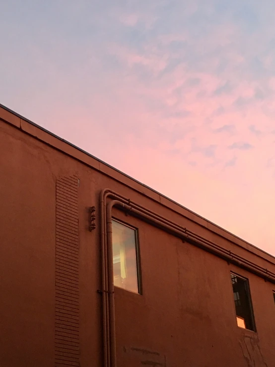 an airplane flying above a building under a blue and pink sky