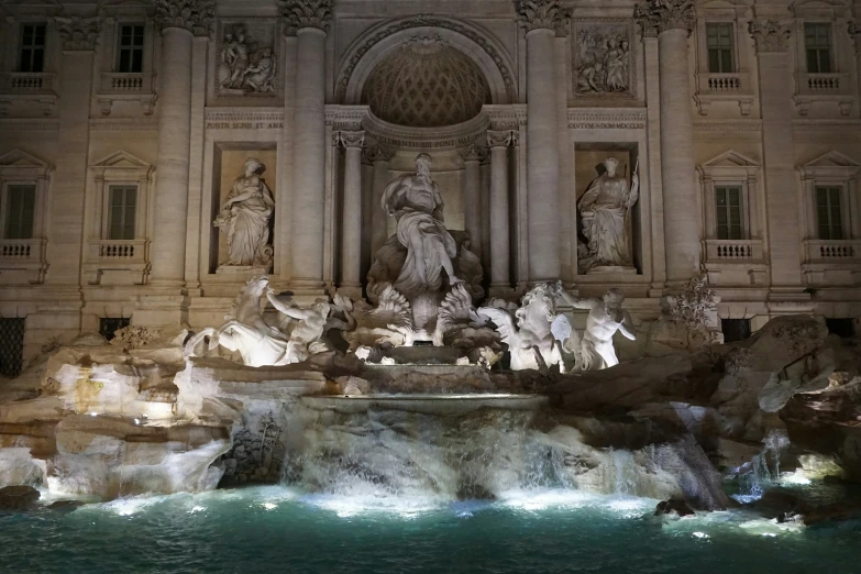 a fountain lit by lights in a city