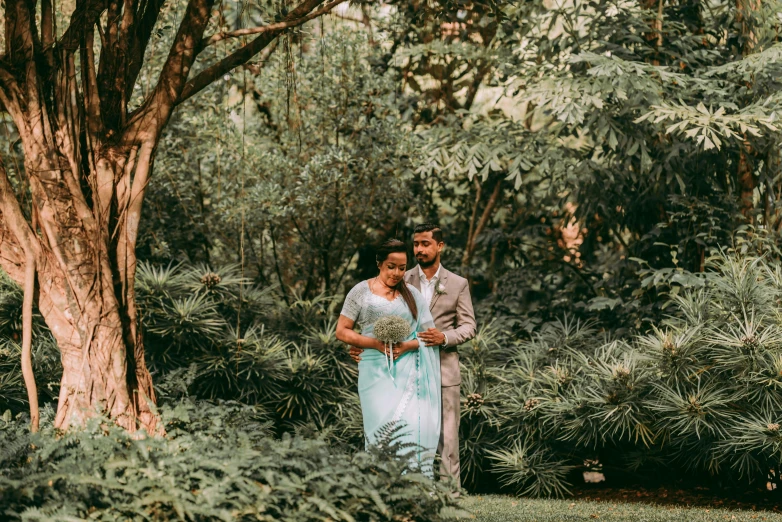 a bride and groom standing under a large tree