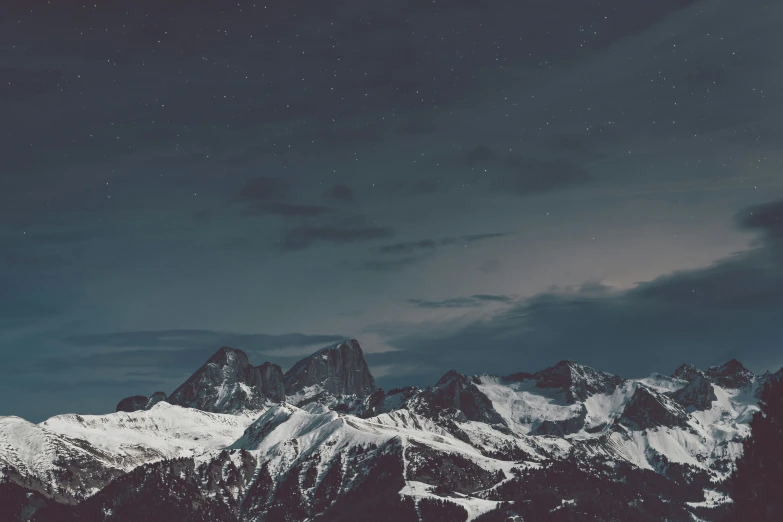 a night time image of snowy mountains under the stars