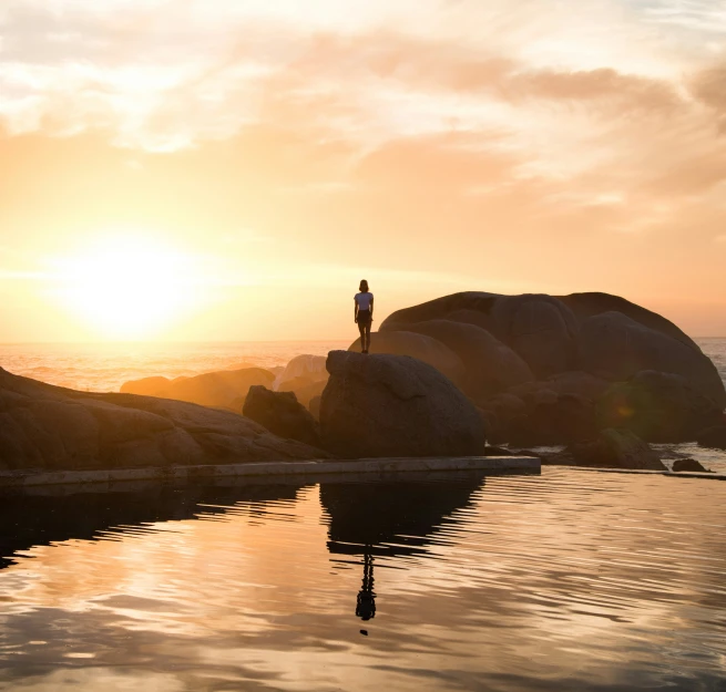 the person is standing on a rock by the water