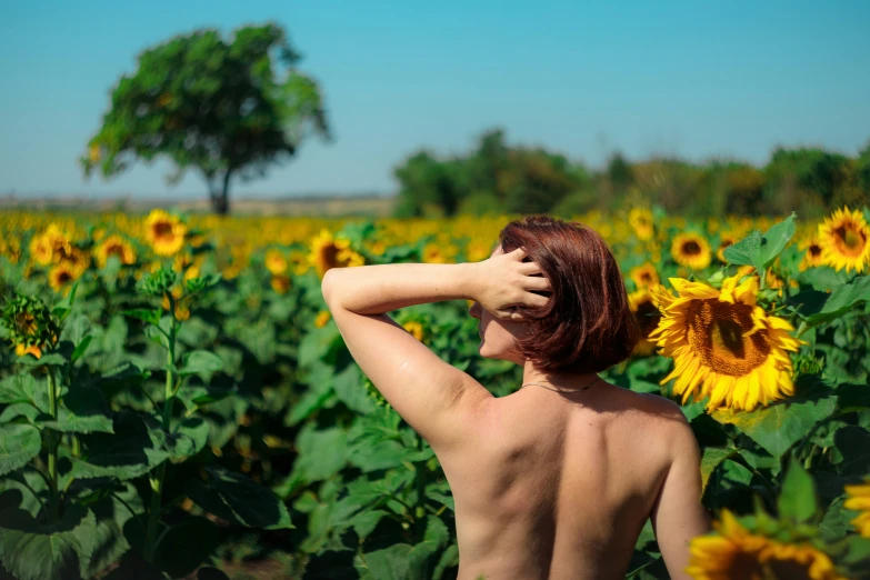 a young woman stands amongst a sunflower field