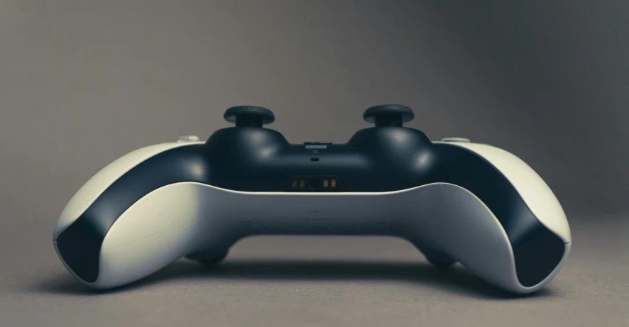 a black and white game controller on a gray background