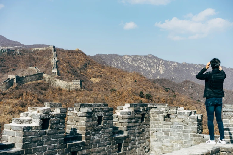 a man taking pos with his cell phone on the great wall