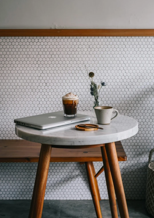 a laptop on a table with a vase of flowers