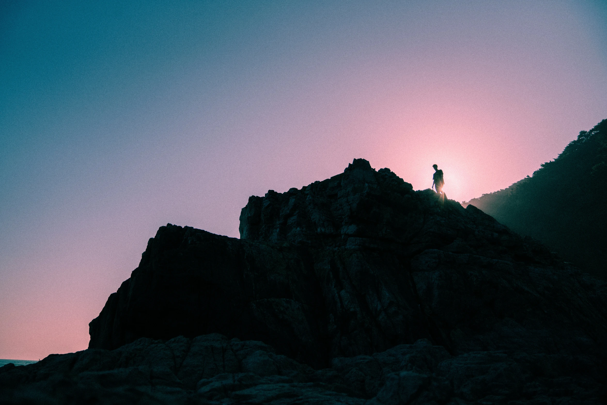 the sun is setting over a mountain peak