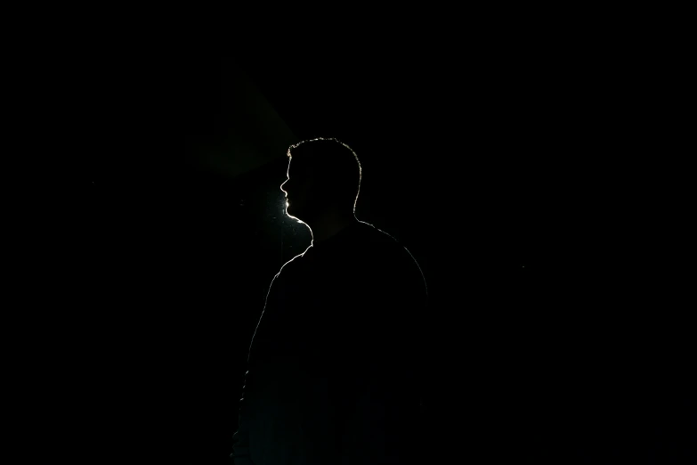 a man standing up against a dark background