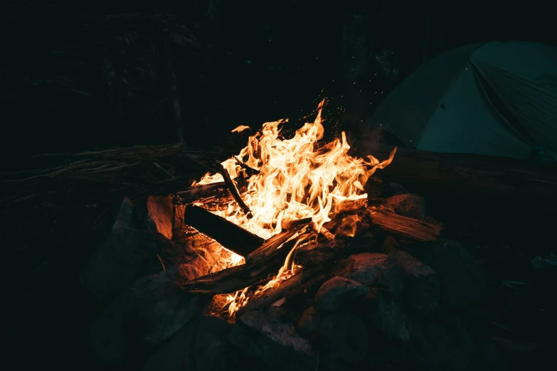 a camp fire with the glowing orange blaze lit