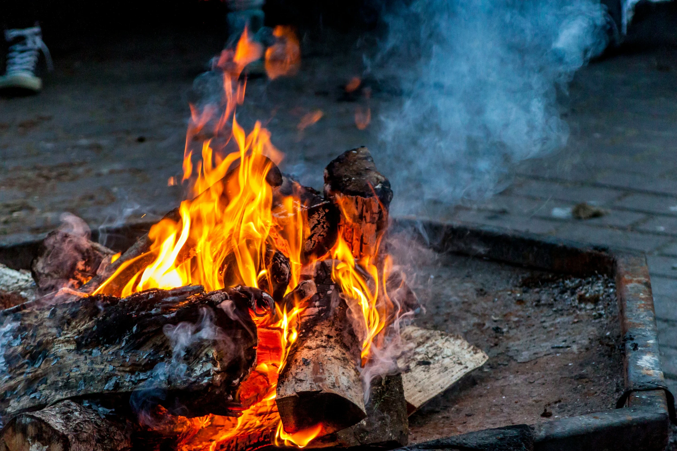 fire blazing on the ground near a small wooden structure