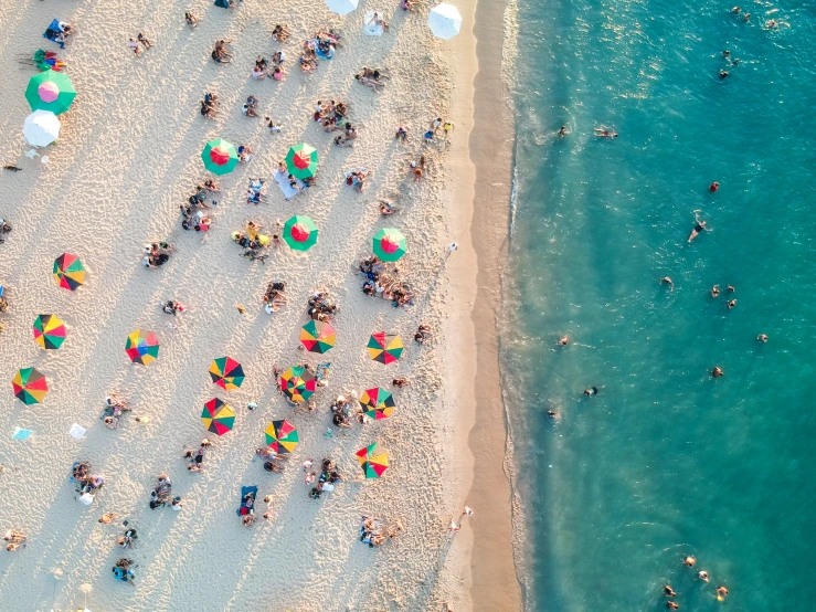 people are gathered on the beach in their bathing suits