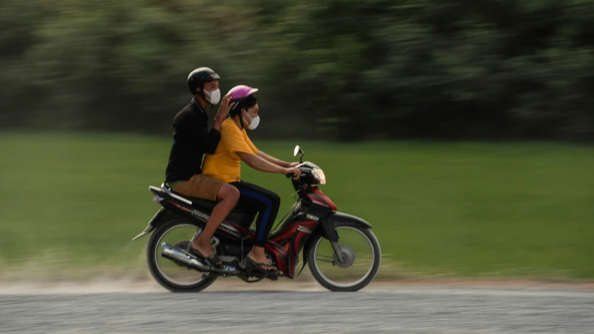 two people riding on the back of a motorcycle