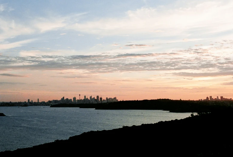 sunset on the water with a large cityscape in the distance