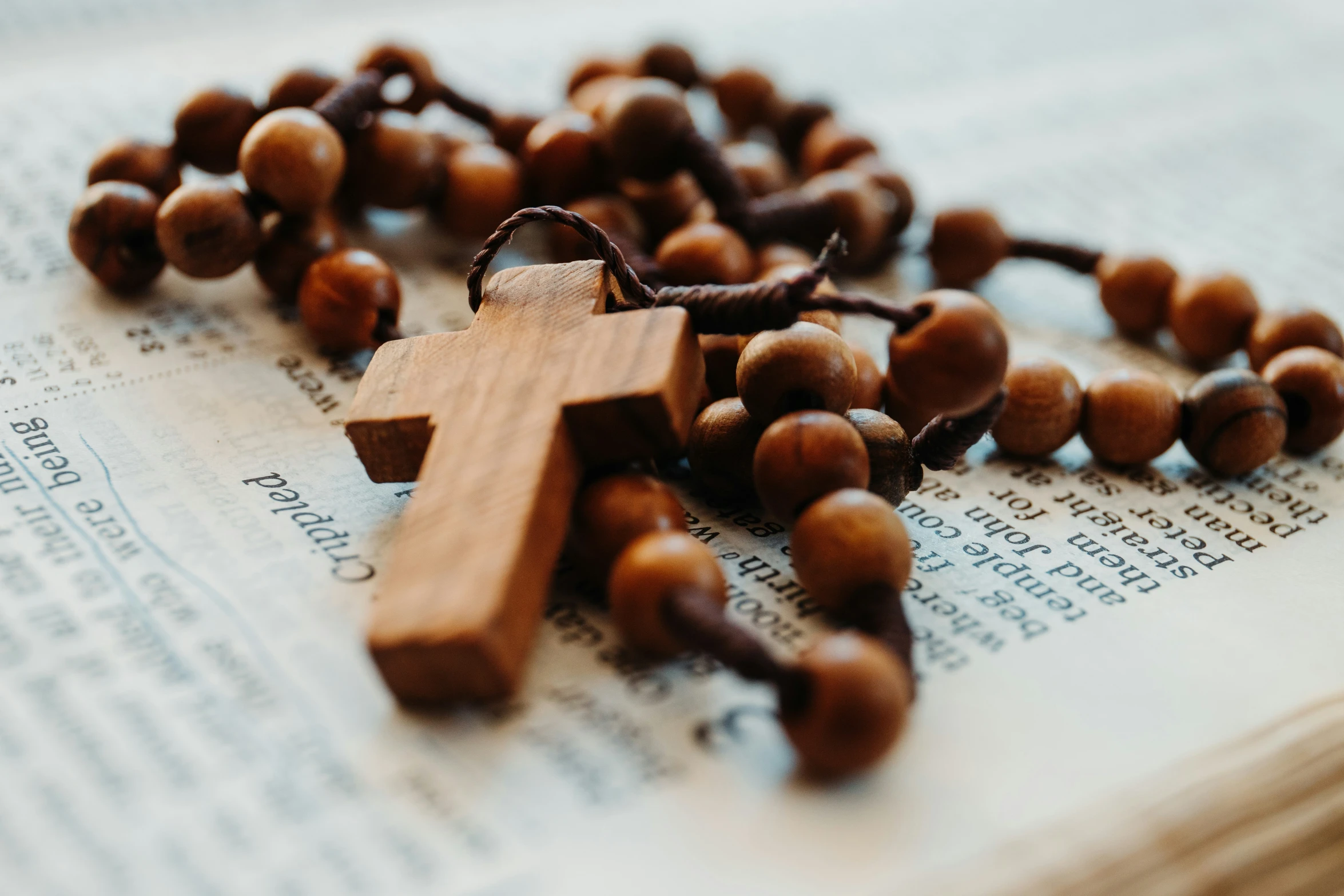 a rosary and a wooden cross on top of a book