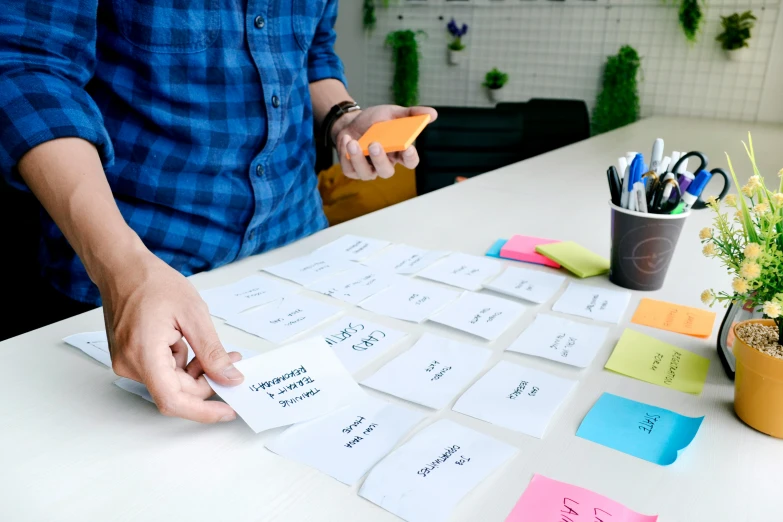 a man that is working on a table with many sticky notes