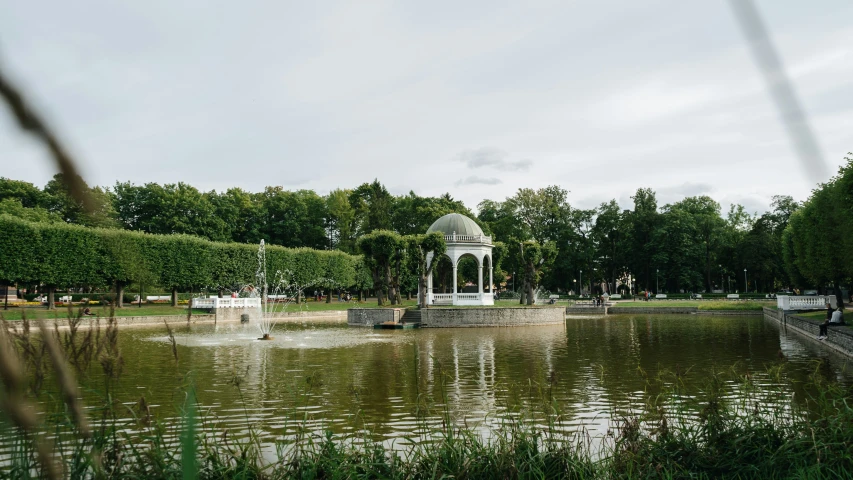 a gazebo in a park next to a pond