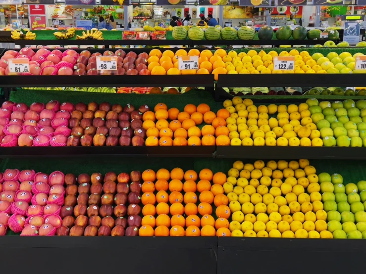 the shelves in the market have oranges, raspberries and apples