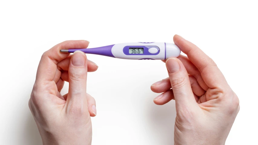 a woman holding an electronic thermometer while wearing her hair