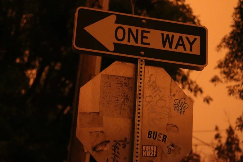 a one way sign next to an intersection with stickers and graffiti on it
