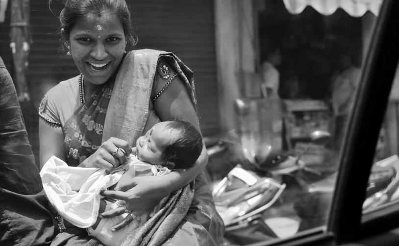 a black and white image of a smiling woman holding a baby