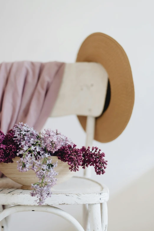 a small wooden bowl with purple flowers on top of a chair