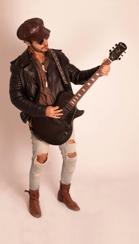 the musician is wearing sunglasses, boots and a leather jacket