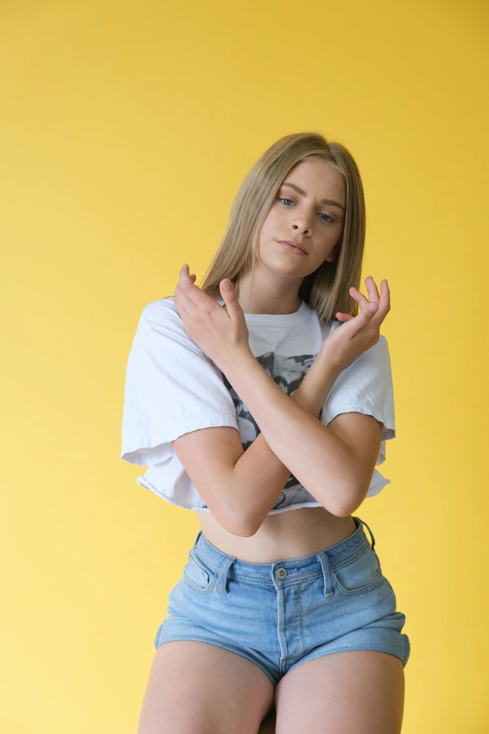 a young woman posing in a white t - shirt and denim shorts