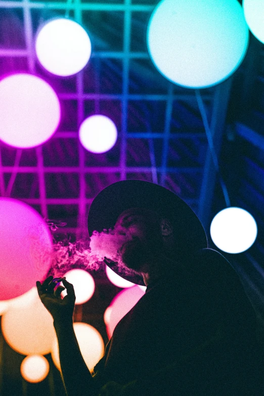 a person in black jacket smoking and colorful lights