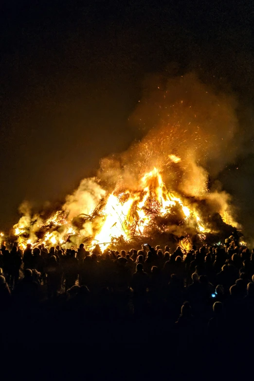 large crowd gathered around bonfire at night time