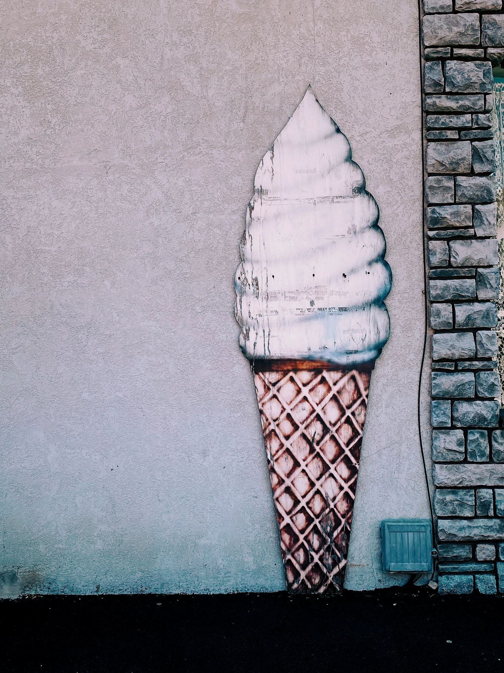 an ice cream cone sits next to a brick wall