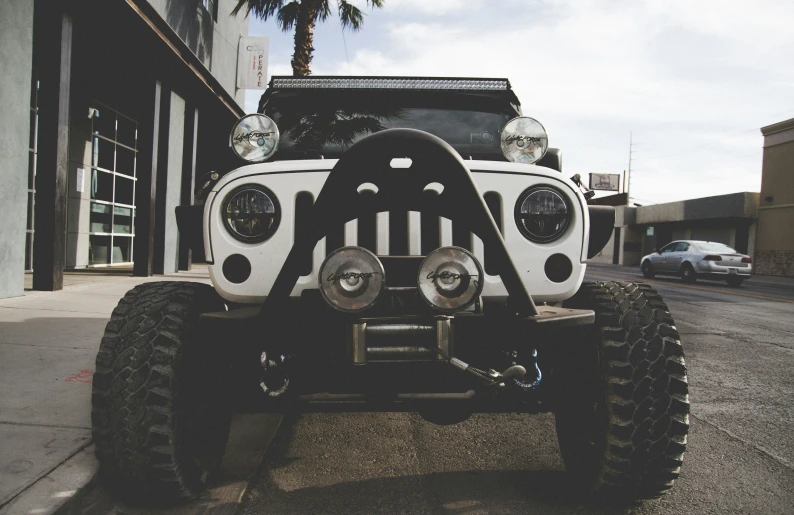 a jeep driving down the road with a big wheel