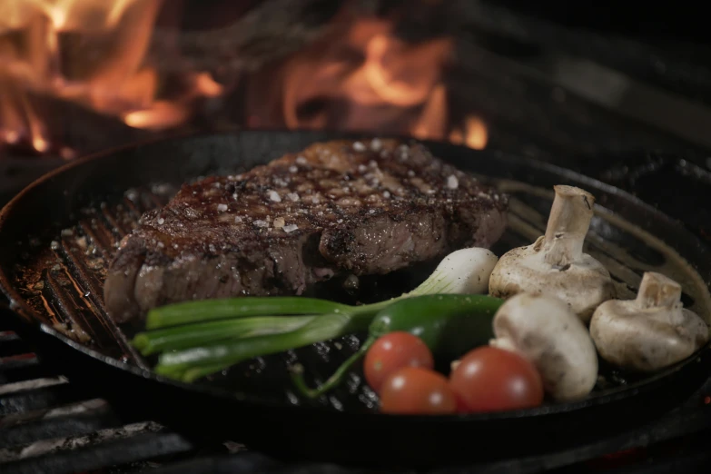 steak, mushrooms and vegetables cooking on a griddle