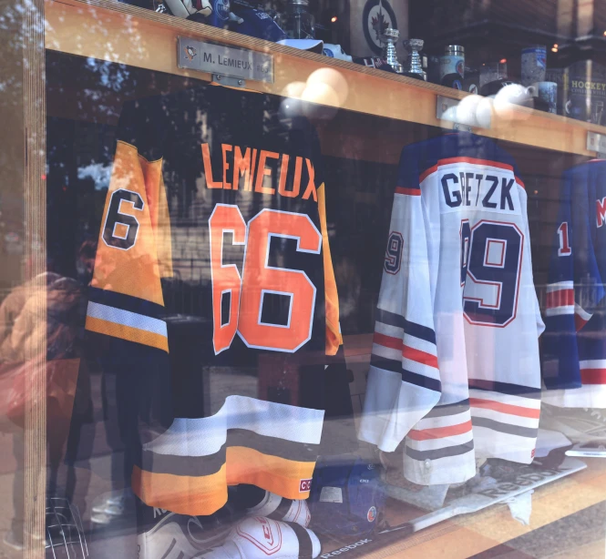 hockey jerseys and sports equipment sit in a window